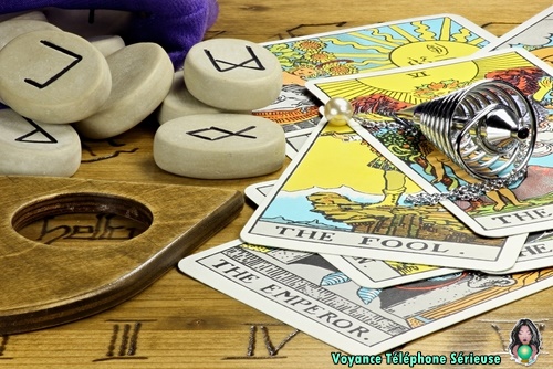 cartes de voyance étalées sur une table de oui ja, tarot, runes et pendule de voyance